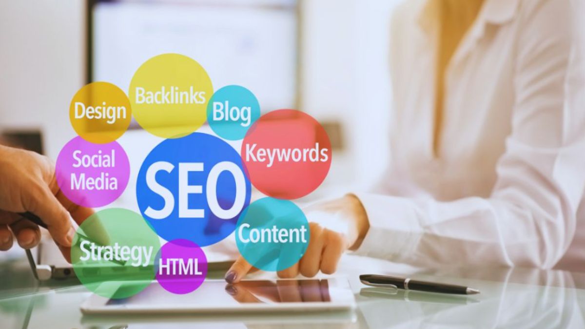 A business meeting setting where two people discuss SEO strategies, shown through colorful circles labeled design, backlinks, blog, keywords, content, social media, strategy, and HTML, representing services offered by an SEO company in Kendall.
